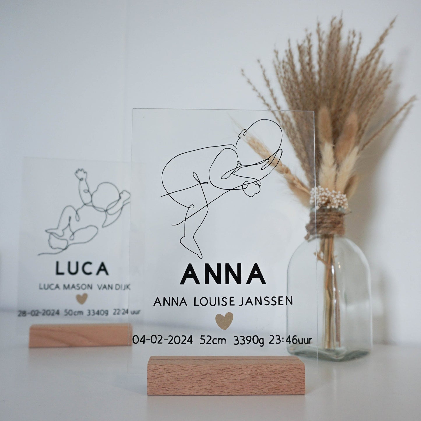 Een vergelijking tussen het geboorteframe Anna en Luca, beide met unieke line art illustraties.