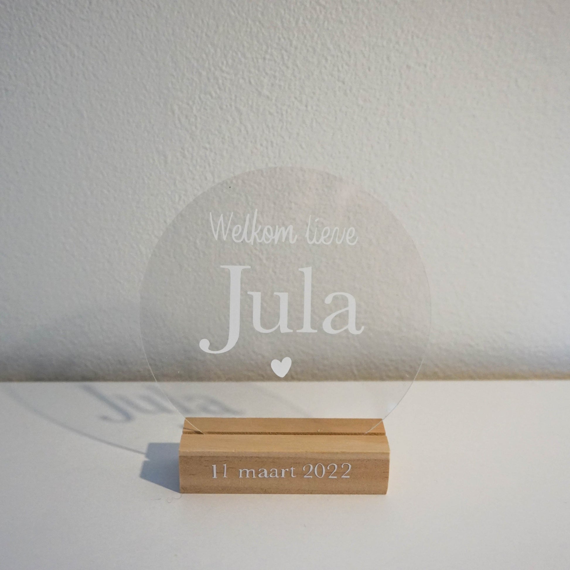 Close-up van een transparante geboortecirkel met de tekst "Welkom lieve [Jula]" in helder wit.